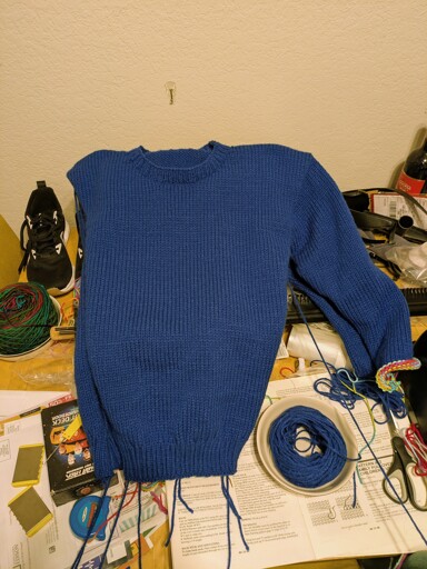 Progress pictures of a blue sweater project being made with a basic knitting machine