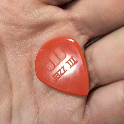 A red guitar pick with the text 'Jazz III'.